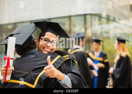 Les élèves en cap and gown hugging Banque D'Images