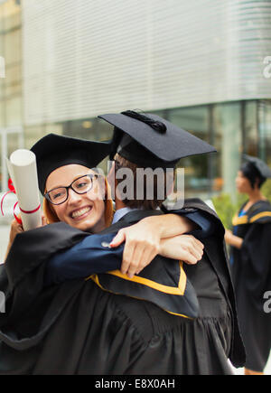 Les élèves en cap and gown hugging Banque D'Images