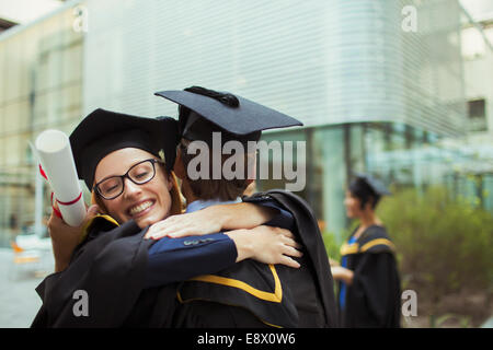 Les élèves en cap and gown hugging Banque D'Images