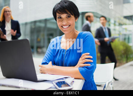 Businesswoman working on laptop à l'extérieur du bâtiment de bureaux Banque D'Images