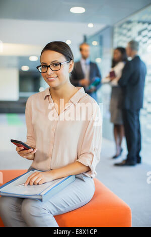 Businesswoman using cell phone in office building Banque D'Images