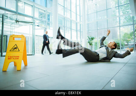 Businessman de glisser sur le plancher du bâtiment de bureaux Banque D'Images