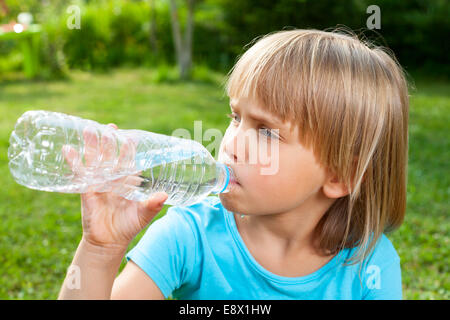 Cute little girl de l'eau potable dans un jardin d'été Banque D'Images