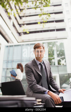 Man sur le banc à l'extérieur du bâtiment de bureaux Banque D'Images