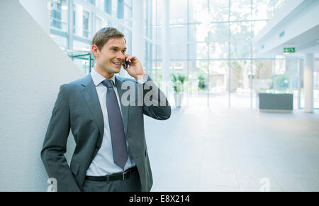 Businessman talking on cell phone in office building Banque D'Images