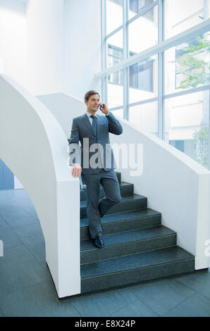 Businessman talking on cell phone descendant des escaliers Banque D'Images