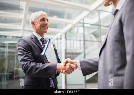 Businessmen shaking hands in office building Banque D'Images