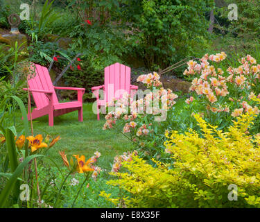 Vashon-Maury Island, WA : un jardin de plantes vivaces d'épine-vinette, alstromeria et d'hémérocalles mène à des chaises aux couleurs vives Banque D'Images