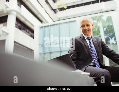 Businessman using laptop in office building Banque D'Images