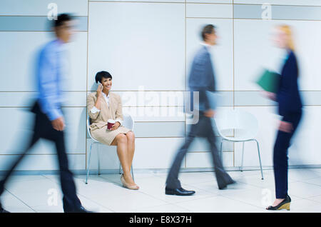 Businesswoman talking on cell phone in office building Banque D'Images