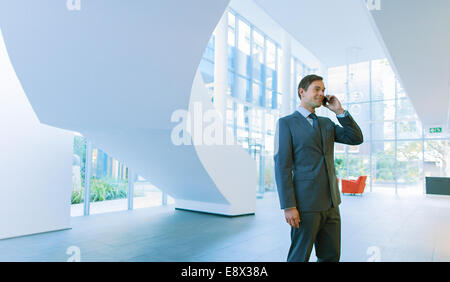 Businessman talking on cell phone in office building Banque D'Images