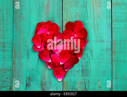 Pétales de rose rouge en forme de coeur en détresse sur porte en bois bleu sarcelle d'antiquités Banque D'Images