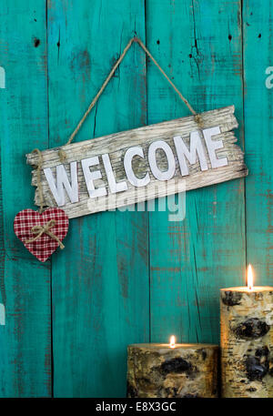 Panneau de bienvenue en bois avec coeur plaid rouge et brûler des bougies accroché sur fond patiné bleu sarcelle d'antiquités Banque D'Images