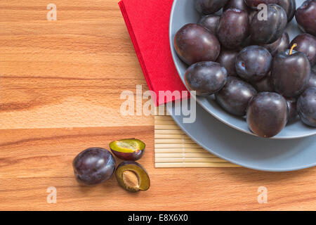 Les prunes fraîches dans bol bleu sur fond de bois. Banque D'Images