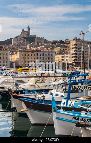 Bateaux de pêche dans le vieux port de Marseille avec la Cathédrale notre dame de la garde sur la colline. Banque D'Images