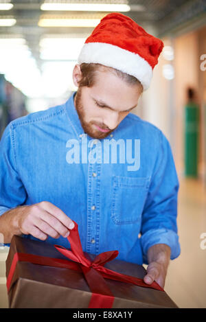 Guy à Santa cap déballage de cadeau de Noël Banque D'Images