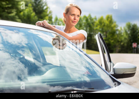 Jeune, jolie, heureuse femme debout par sa voiture, étant un fier propriétaire de son nouveau véhicule Banque D'Images