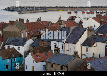 Vue de haut sur les toits de petite et pittoresque des chalets, de bateaux dans le port et la mer au-delà - village balnéaire de Staithes, North Yorkshire, Angleterre, Royaume-Uni. Banque D'Images