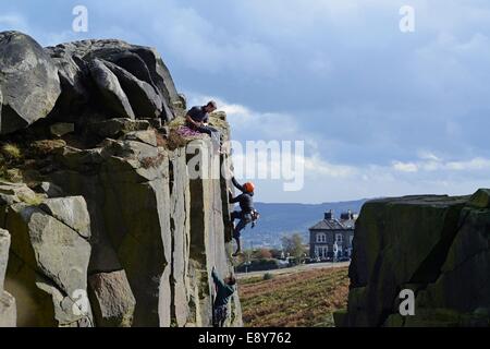 Les jeunes hommes avec un instructeur sur en cours d'escalade sur rochers, Veau Vache et Ilkley Moor, Yorkshire Banque D'Images