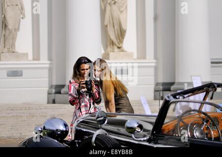 Deux femmes, debout devant une voiture classique, regardez la photo l'un d'eux vient de prendre sur la caméra elle est tenue Banque D'Images