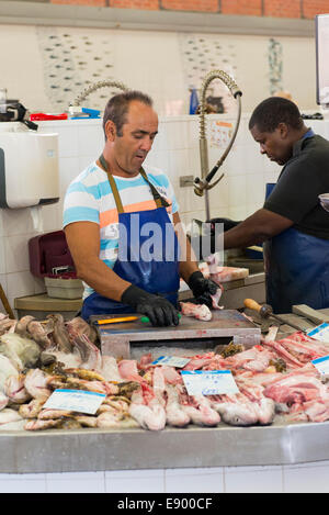 Portugal Algarve Olhao port market town homme chauve tablier bleu gants noirs l'éviscération du poisson rose rouge préparation de nettoyage à vendre Banque D'Images