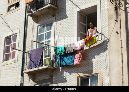 Portugal Lisbonne Alfama appartement sol carrelé typique de la vieille dame noire bloc fascia woman hanging lave-linge sur le balcon de ligne Banque D'Images