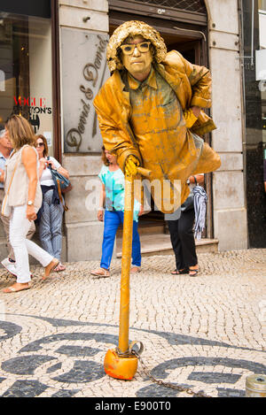 Portugal Lisbonne Chiado Rua Garrett rue pavées de galets artiste musicien ambulant artiste mime dans golden outfit regarde comme si en vol Banque D'Images