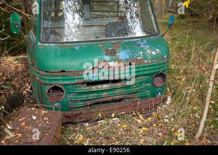 De vieilles voitures qui rouillent dans une forêt entre les maisons anciennes Banque D'Images