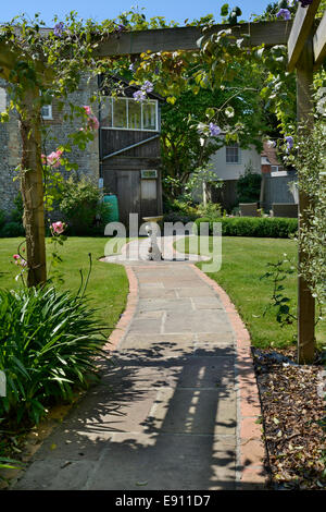 Jardin pavé chemin menant d'une pergola à maison dans le Sussex, Angleterre Banque D'Images