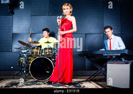 Chanteur professionnel asiatique batteur et clavier à enregistrer de nouveaux morceau ou l'album en studio Banque D'Images