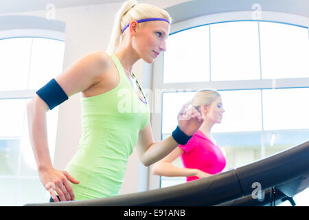 Les femmes en salle de fitness faire du sport s'exécutant sur un tapis roulant Banque D'Images