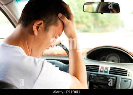 Jeune homme fatigué ont un mal de tête pendant la conduite car.concept de transport Banque D'Images