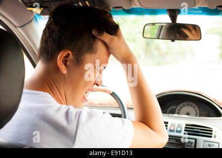 Jeune homme fatigué ont un mal de tête pendant la conduite car.concept de transport Banque D'Images