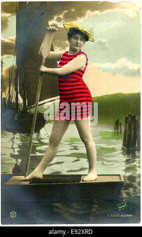 Femme en maillot rayé rouge debout sur un bateau avec Oar, Hand-Colored, carte postale, vers 1900 Banque D'Images