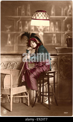 Panache Smiling Woman Wearing Hat assis sur le tabouret et tenant une canne, Hand-Colored Carte Postale, vers 1910 Banque D'Images