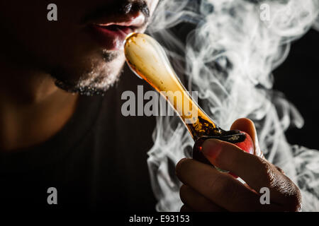 Shoot Studio avec modèle de simulation du pot de fumer avec un tuyau à l'obscurité dans une image à contraste élevé Banque D'Images