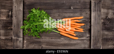 Botte de carottes fraîches avec des feuilles vertes sur fond de bois. Légume. L'alimentation Banque D'Images