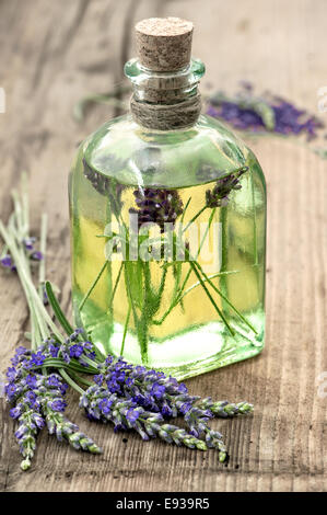 Bouteille d'huile de lavande avec les fleurs fraîches sur fond de bois sain. herbes. selective focus Banque D'Images