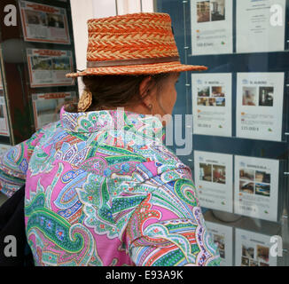 Femme avec chapeau à la recherche dans la fenêtre de l'agent immobilier en Espagne, Fuengirola. L'Espagne. Banque D'Images