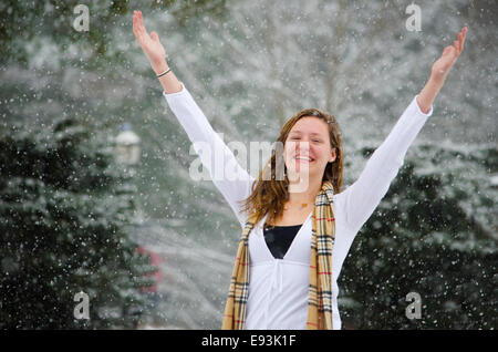 Let it Snow : Une jeune femme levait les bras en signe de victoire d'une belle averse de neige. Banque D'Images