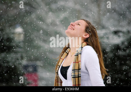 Let it Snow : Une jeune femme levait les bras en signe de victoire d'une belle averse de neige. Banque D'Images