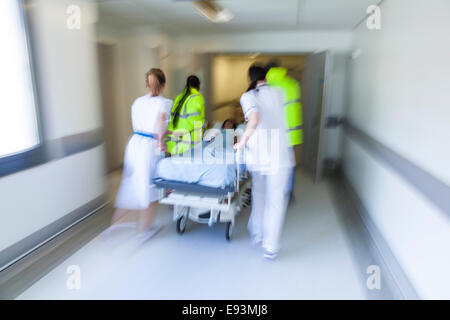 Motion blurred photo d'enfant patient sur civière ou gurney, poussé dans couloir de l'hôpital par les ambulanciers et les médecins Banque D'Images