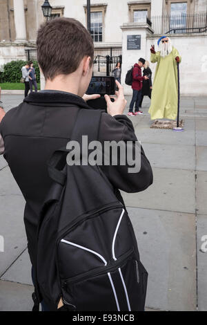 Prendre une photo touristique sur un téléphone intelligent d'un artiste de rue à Trafalgar Square, Londres Banque D'Images