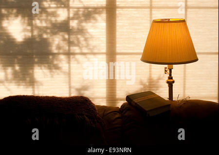 Bible sur l'arrière de la table avec la lumière solaire et la lumière chaude du feu avec des lunettes Banque D'Images