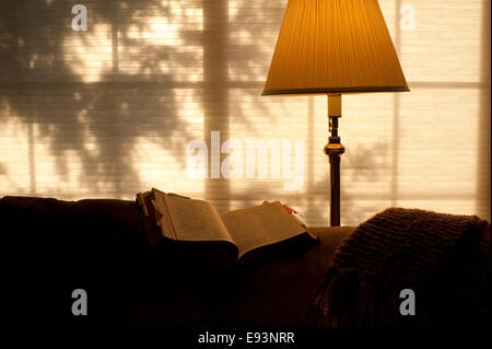 Bible ouverte sur l'arrière de la table avec la lumière solaire et la lumière chaude du feu Banque D'Images