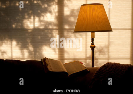 Bible ouverte sur l'arrière de la table avec la lumière solaire et la lumière chaude du feu Banque D'Images