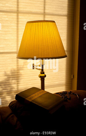 Bible sur l'arrière de la table avec la lumière solaire et la lumière chaude de la lampe avec rosaire Banque D'Images