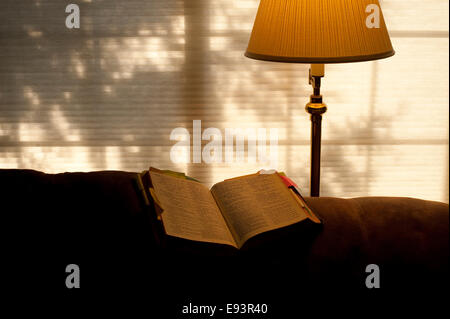 Bible ouverte sur l'arrière de la table avec la lumière solaire et la lumière chaude du feu Banque D'Images