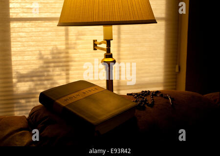 Bible sur l'arrière de la table avec la lumière solaire et la lumière chaude de la lampe avec rosaire Banque D'Images