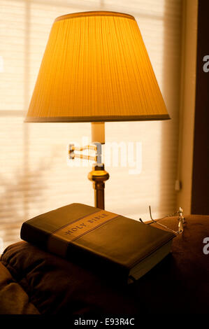 Bible sur l'arrière de la table avec la lumière solaire et la lumière chaude du feu avec des lunettes Banque D'Images